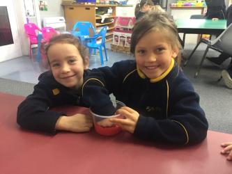 17 Paige and Indie J pressing play dough into the bottom of their container2